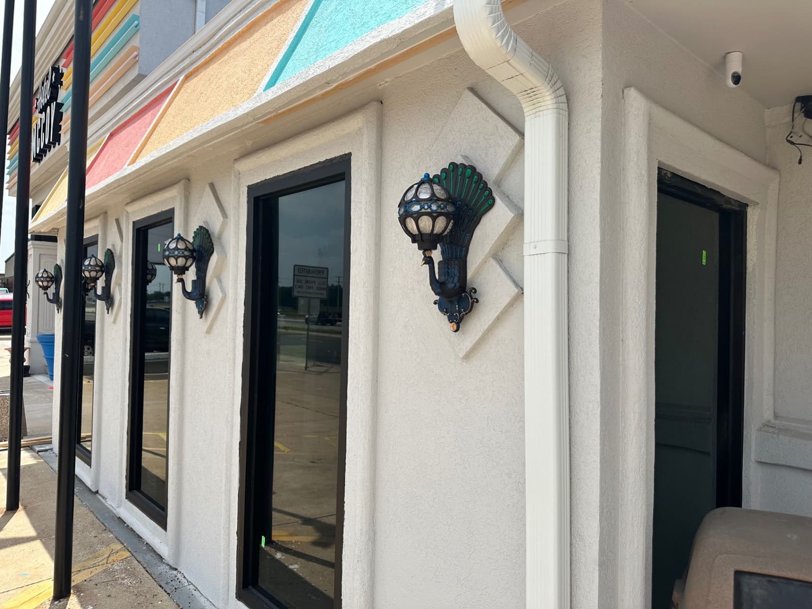 Exterior wall with decorative sconces and dark-framed doors