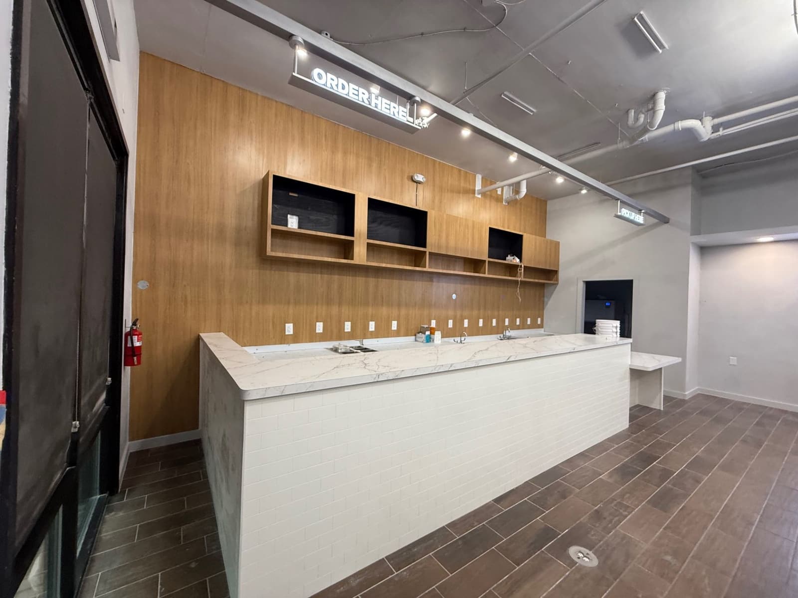 White service counter with wood wall finish and overhead order signage