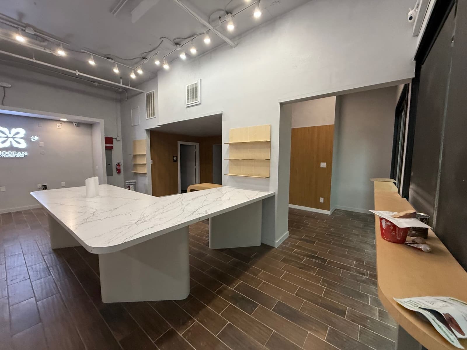 Commercial interior with white counter, shelving, and wood wall finish